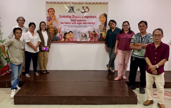 MAGI Staff standing on either side of the 35th Anniversary banner